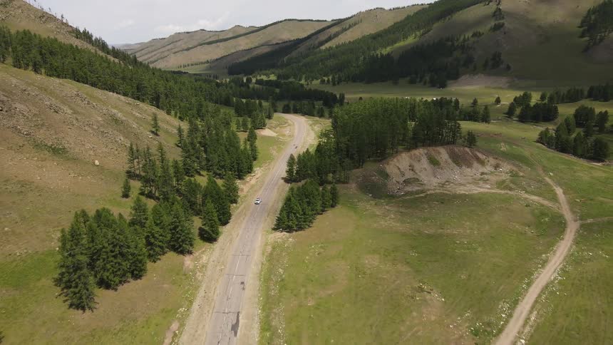 Cars travel down the road by the mountains