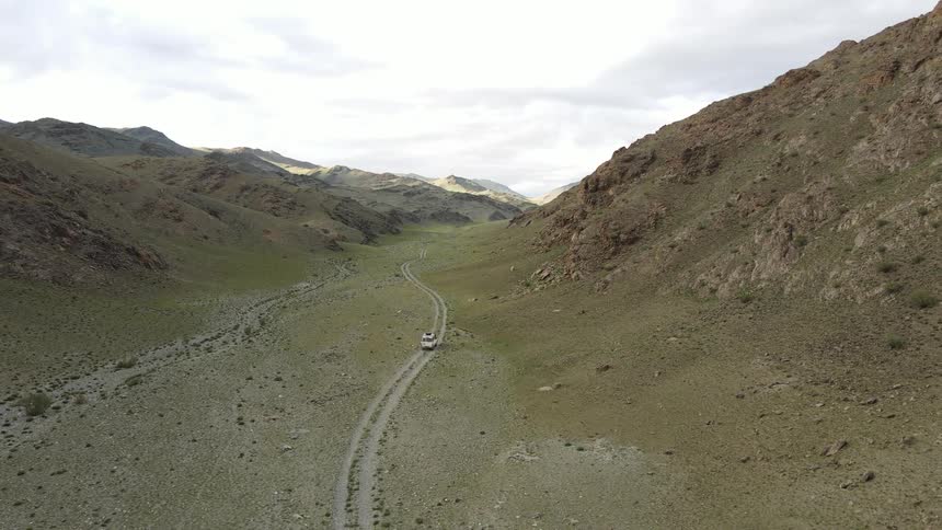 Aerial view of a white jeep driving down a valley