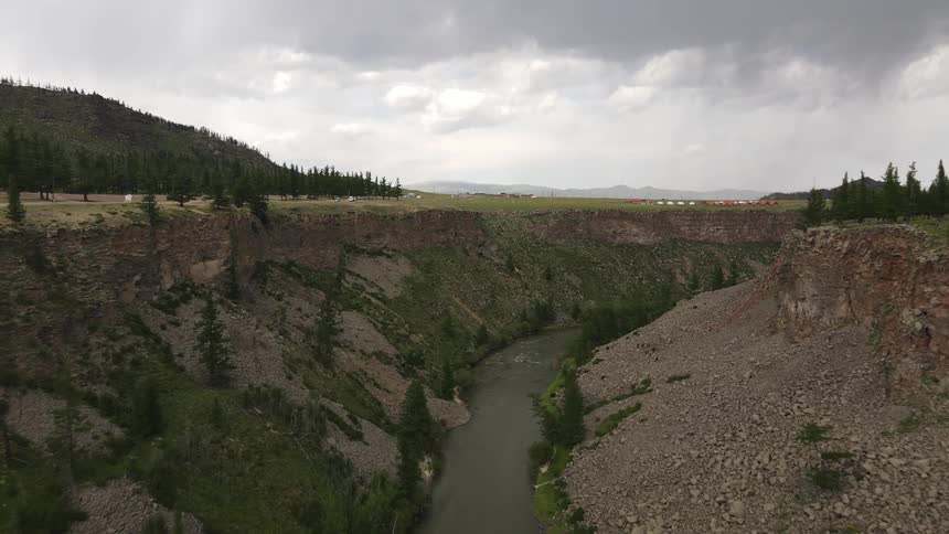 A valley with water near mountains on a cloudy day