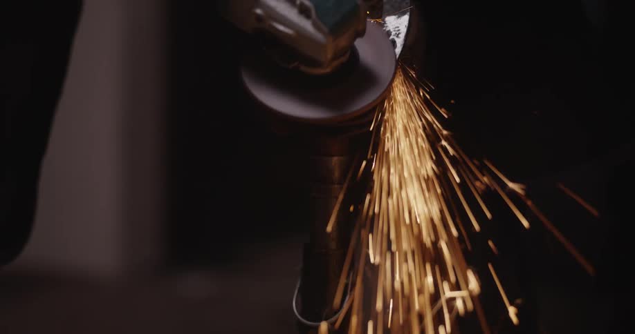 A person uses a rotating power tool to grind the surface of a horseshoe