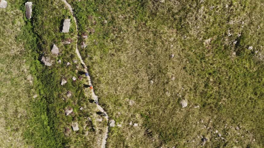 An aerial clip of hikers walking a narrow path