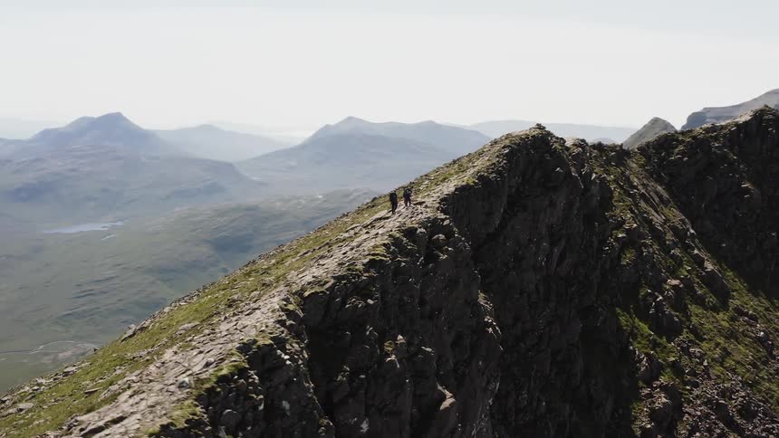 Mountaineers with a dog walk over the ridge of a mountain