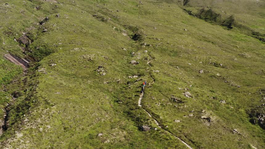 Hikers walking on a path on a plateau near mountains