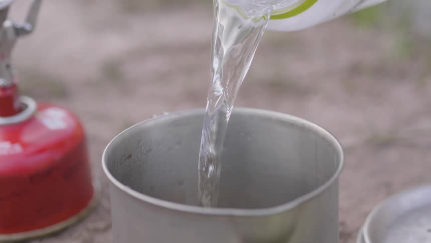 A bottle of water being poured into a cup