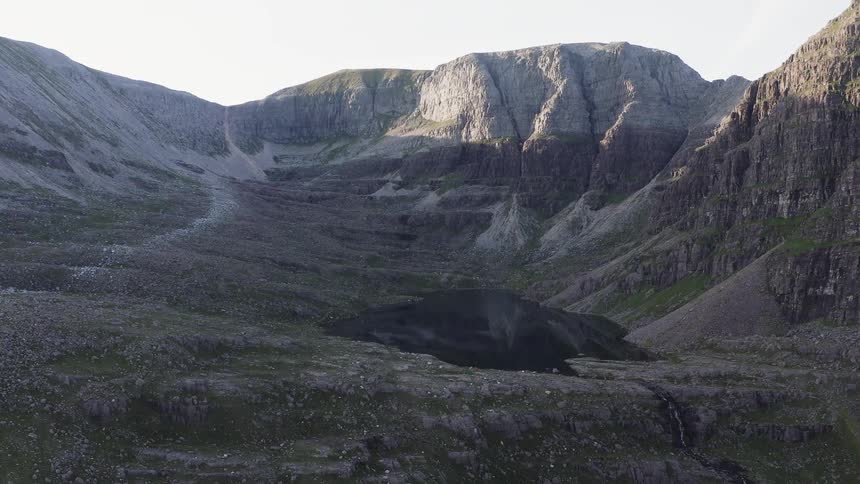 Aerial view of a small dark lake in the mountains at morning