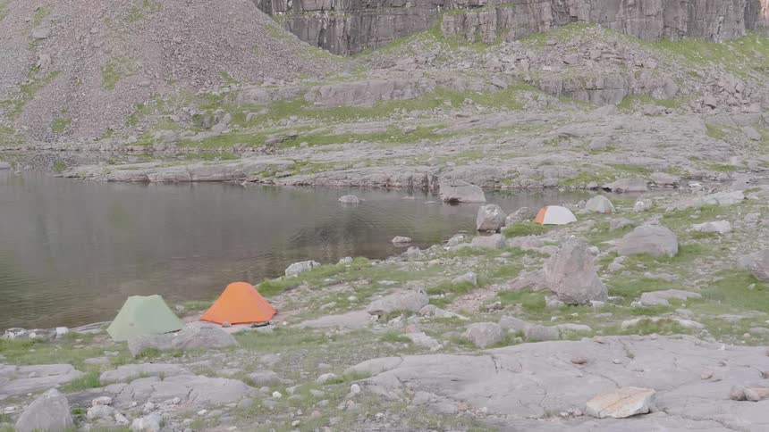 Colorful tents on the shore of a lake in the mountains