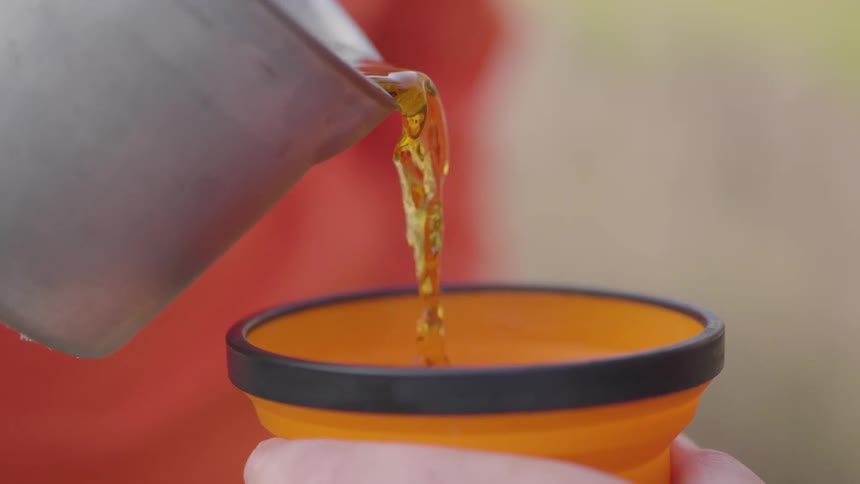 A clip of a person pouring a drink into another persons cup