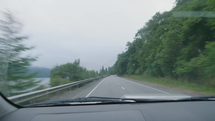 Car driving on a road next to a river in the mountains