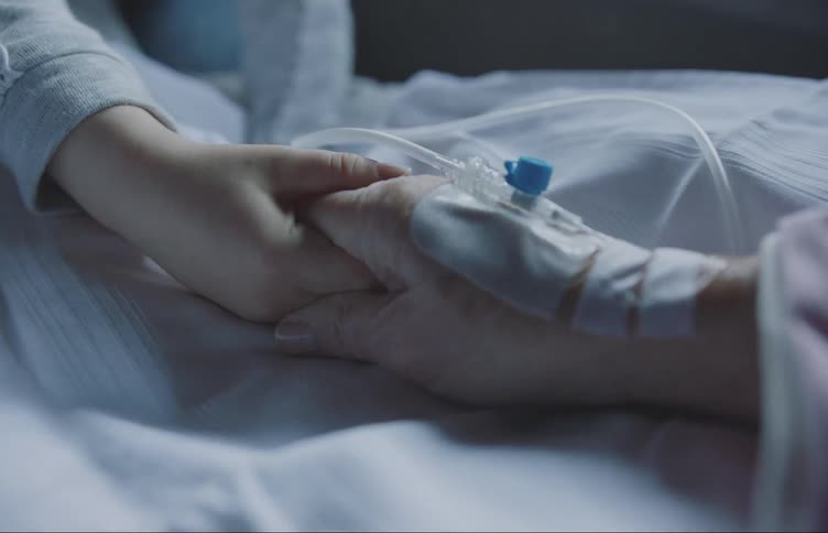 A hand offering comfort to another hand with an iv line in the hospital