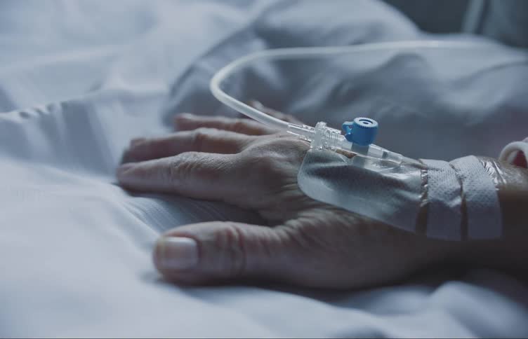 An elderly human hand with medical equipment attached to it