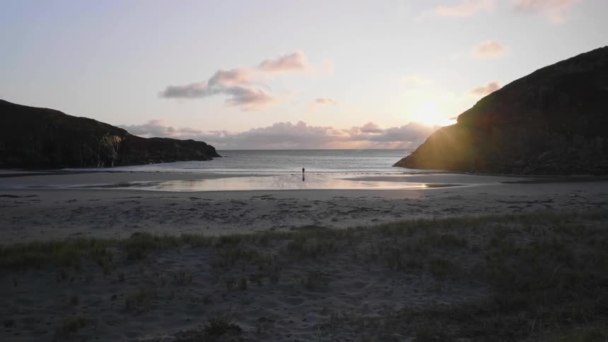 A person alone on the deserted beach during sunset
