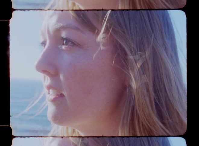 Face of a woman with her hair blowing in the wind next to the ocean