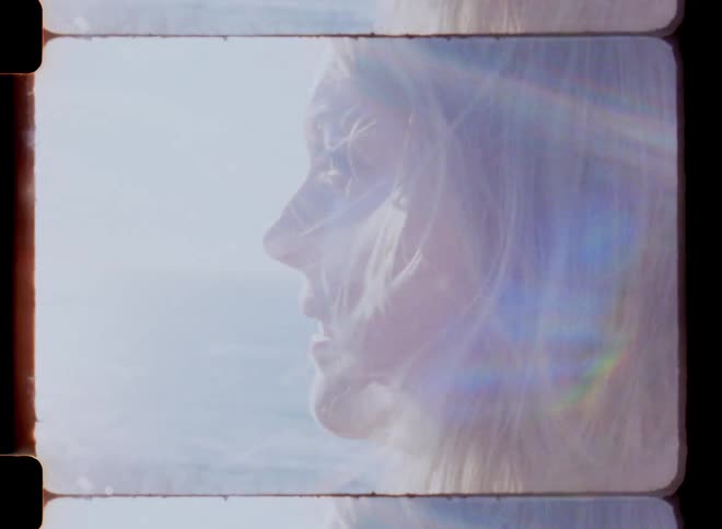 A females head and hair blowing in the wind in front of water