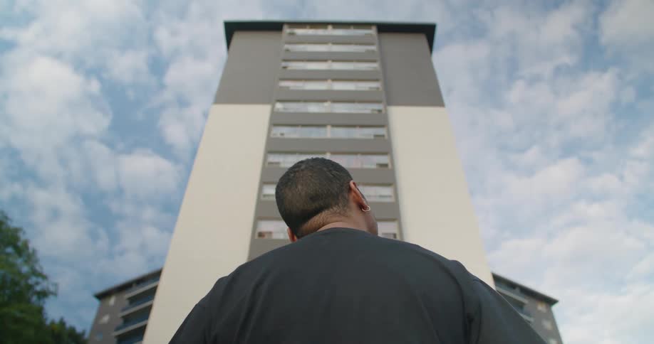 Back of a man looking at a tall building in the city