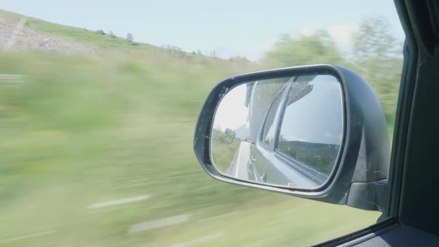Rearview mirror of a car driving through the countryside