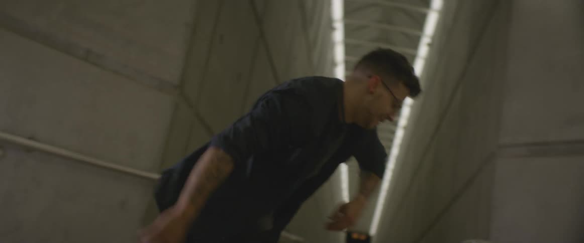 Man with glasses break dances on concrete