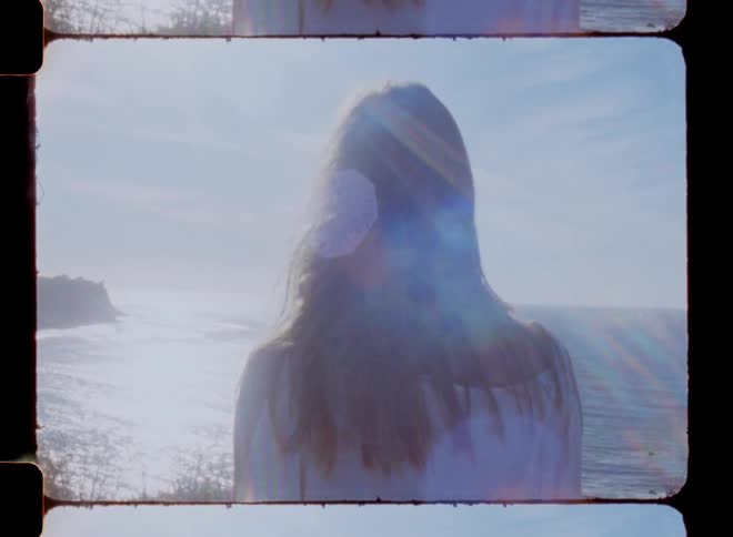A woman facing the ocean on a sunny day