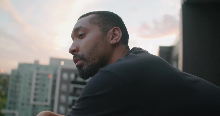 Face of a man looking at the city from a balcony at sunset