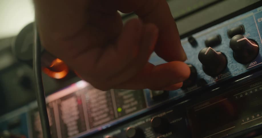 Close up of a musician turning the knob on an amplifier