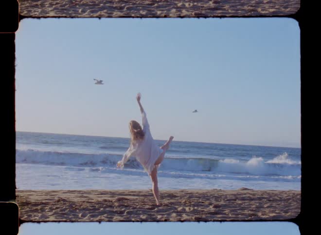 Blonde dancer dances on beach as birds fly past