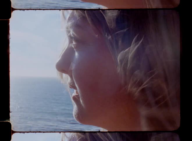 Face of a woman with her hair blowing in the wind next to the ocean