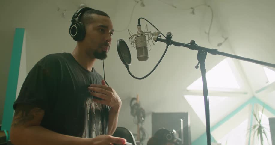 Man stands in front of microphone in recording studio with a technician