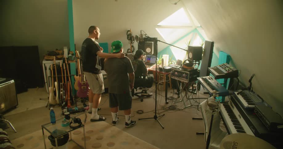 Men sing while standing in recording studio with a recording technician