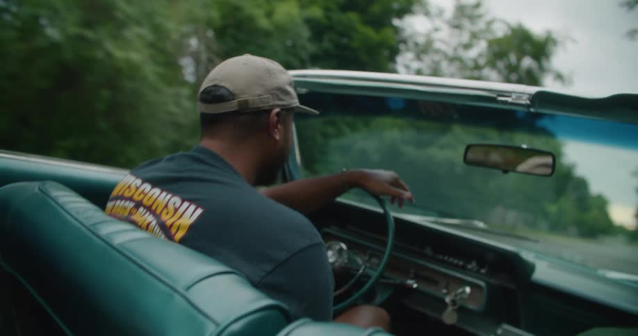 Man driving a classic convertible vehicle while feeling happy and talking