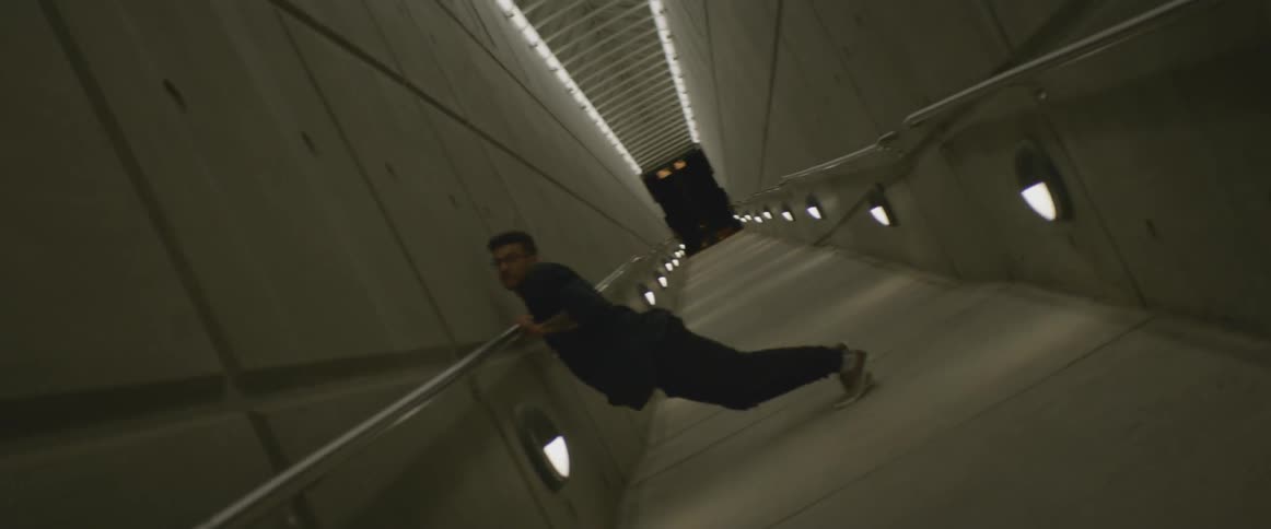 A man dances in a concrete corridor