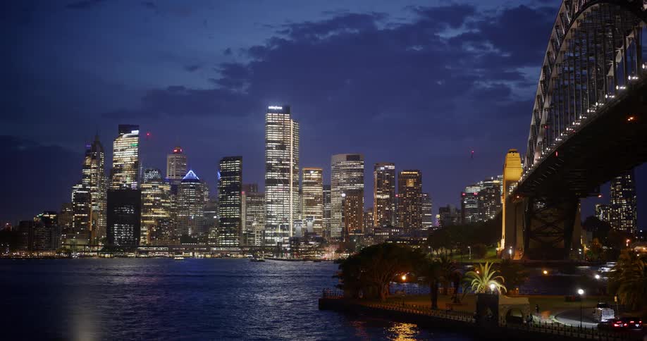 Panorama of a bridge over the sea at night with a metropolis on the horizon