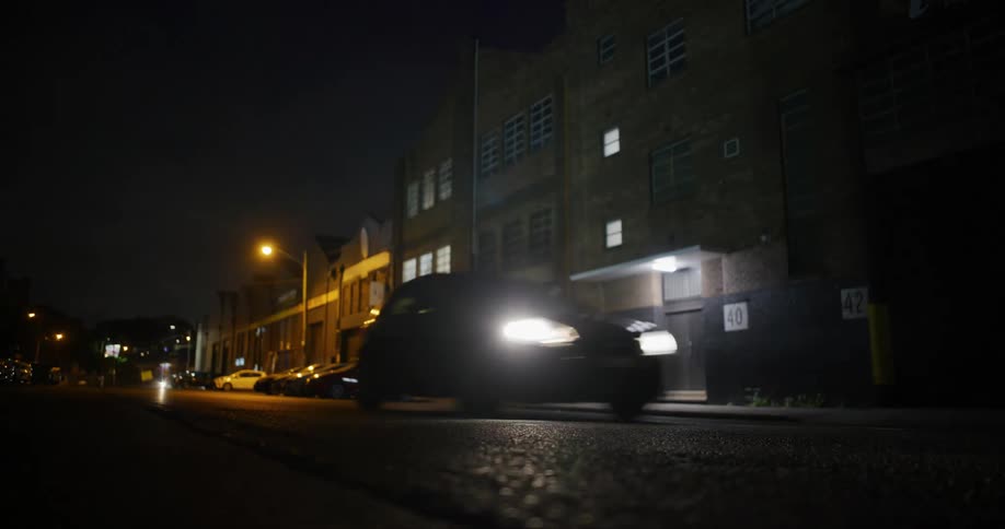 A car and person travel down the street at night