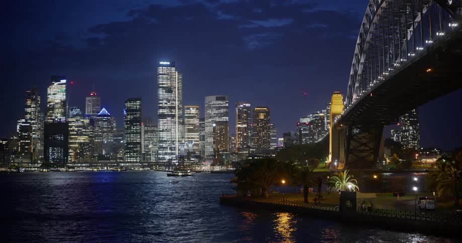 Illuminated skyscrapers and a bridge over the sea at night
