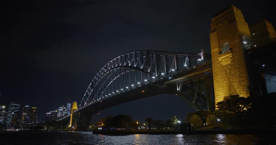 View of a bridge over the sea connecting a metropolis with skyscrapers at night