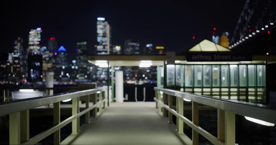 View of an illuminated dock at night with a metropolis of skyscrapers on the horizon