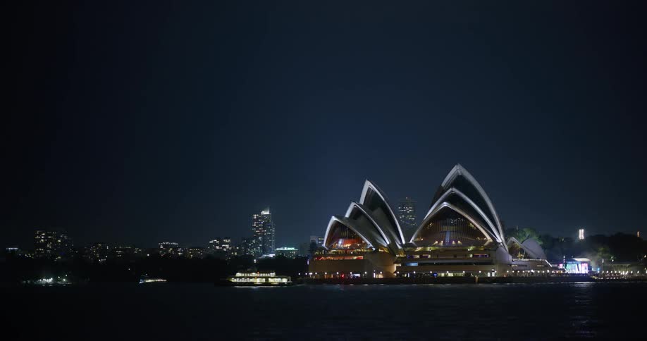 Brightly lit ferryboat passes sydney opera house at night