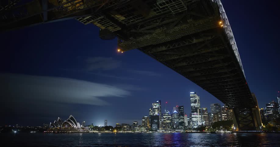 Illuminated city skyline seen from under the suspension bridge