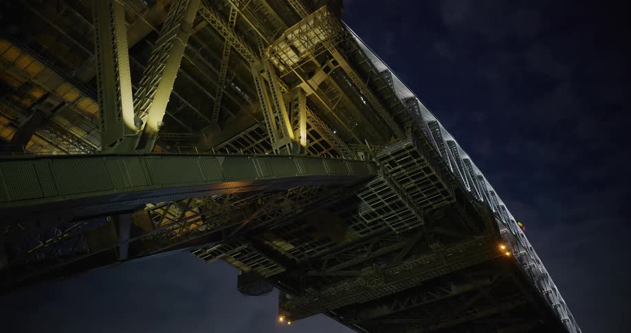 Upward view of the arch of a bridge at night