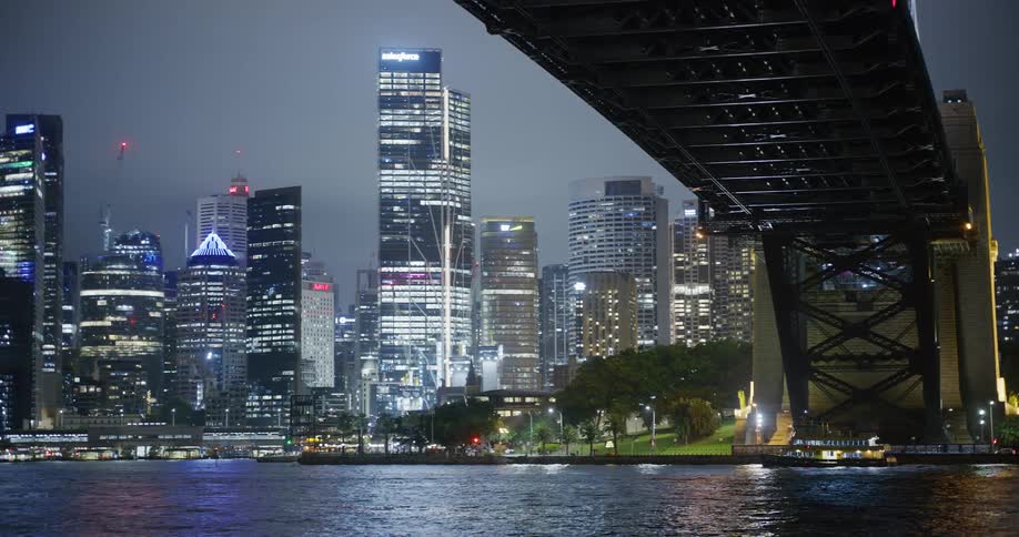 Illuminated city skyline seen from under the suspension bridge