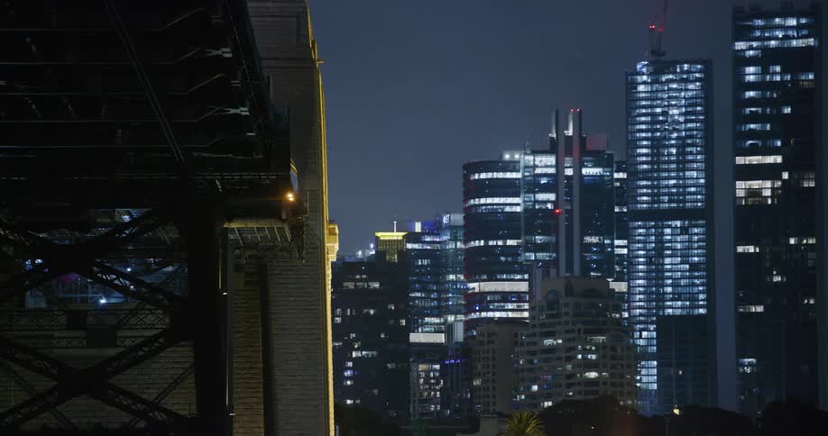 View of the side of a bridge with a glimpse of skyscrapers in a nighttime metropolis