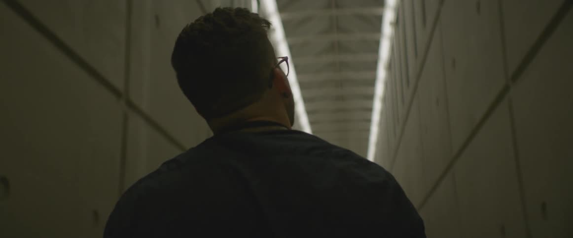 A man walks through a light hallway looking upwards and around