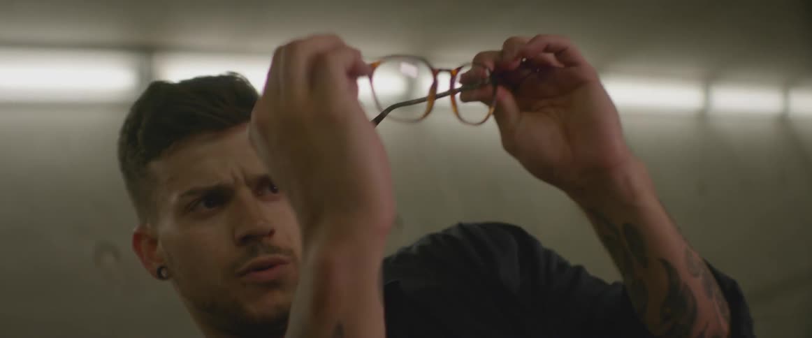 A man pulls off his glasses dramatically in a brightly lit room