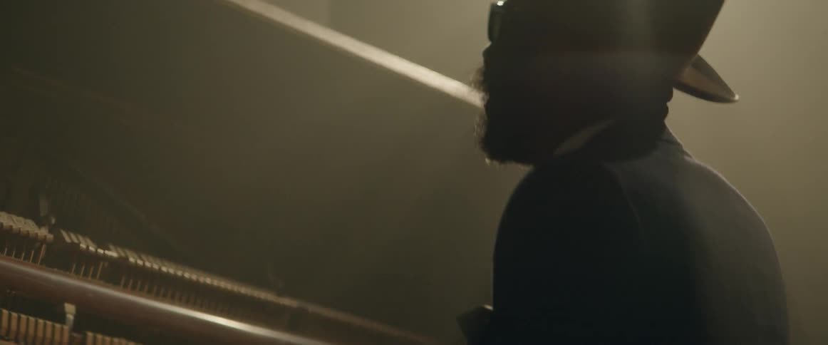A man with a beard and sunglasses plays the piano