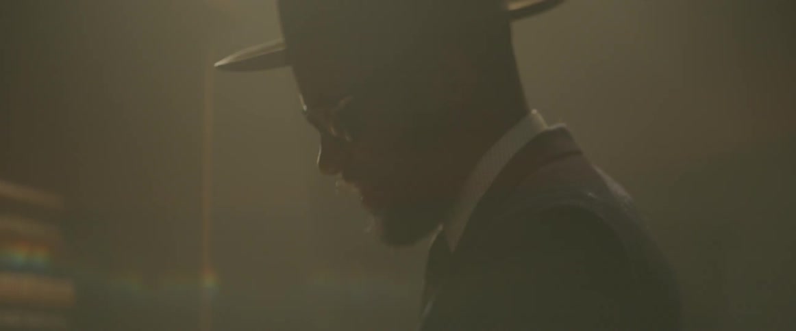 A black man is singing and playing a piano