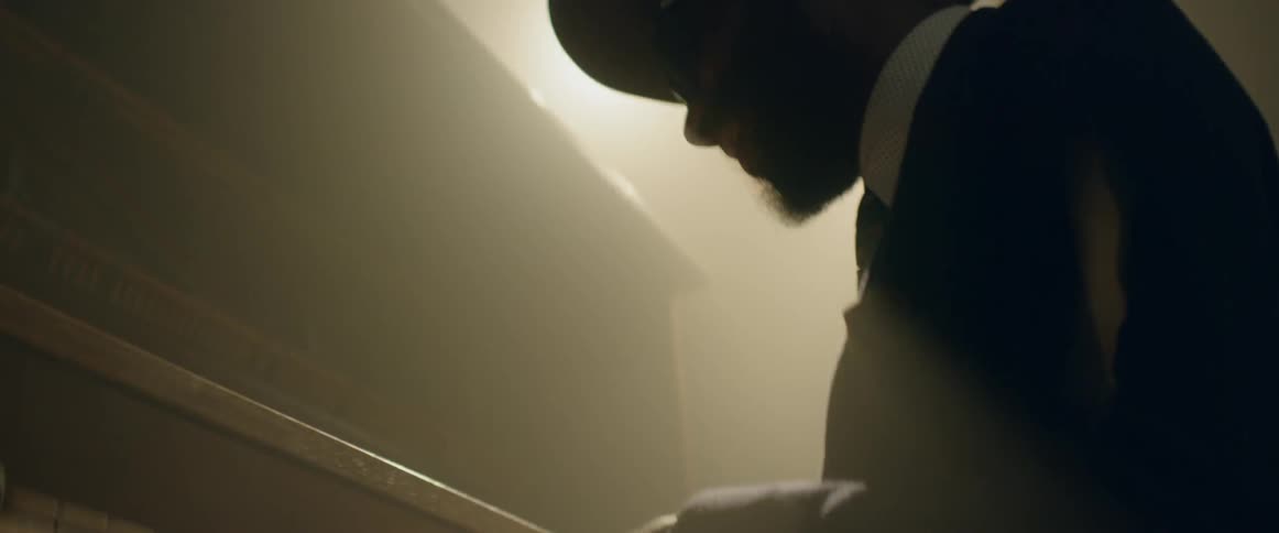 A man in playing piano in a dim room