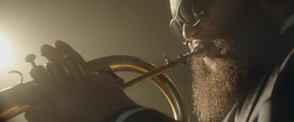 A bearded man is playing a horn