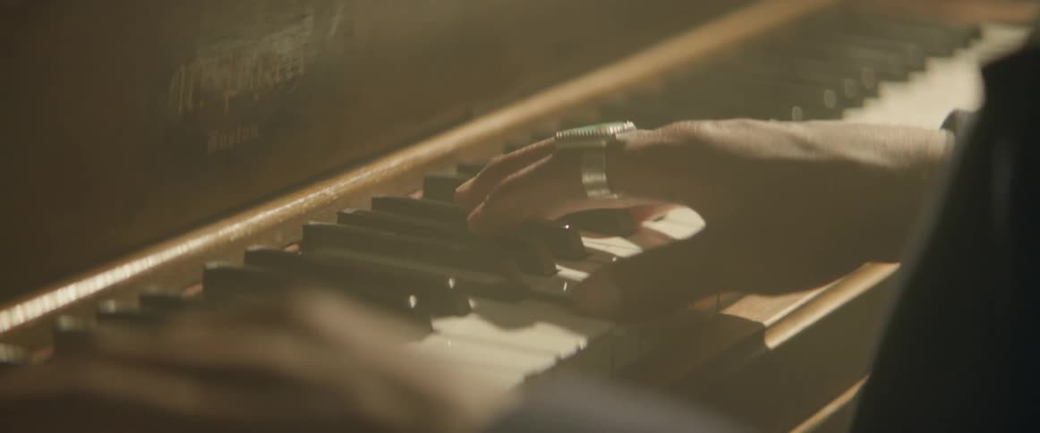 A pianist's hands work the keys on an upright piano