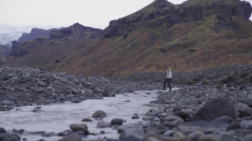 Woman crossing a small river over the rocks