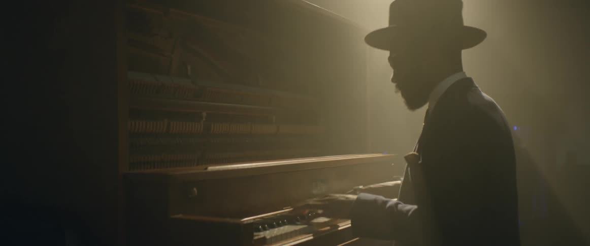 A man is bopping his head while he plays a piano