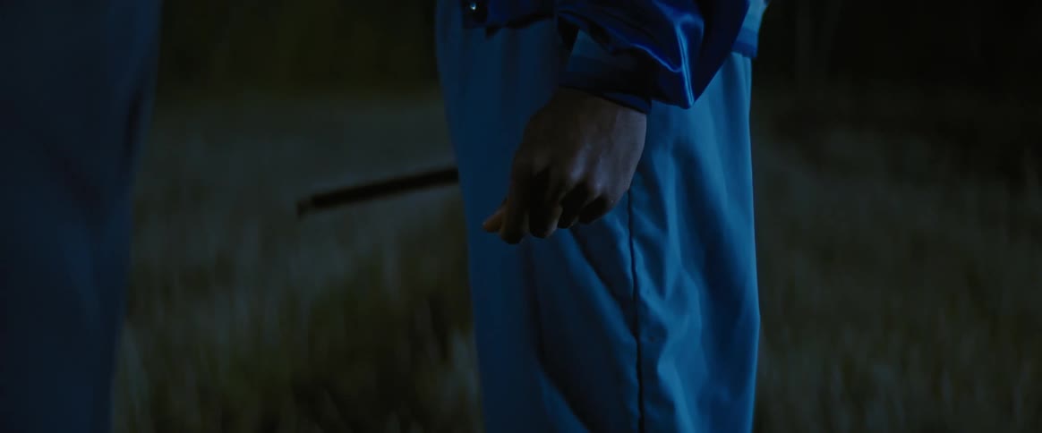 A black person standing on a grass moving his fingers at night