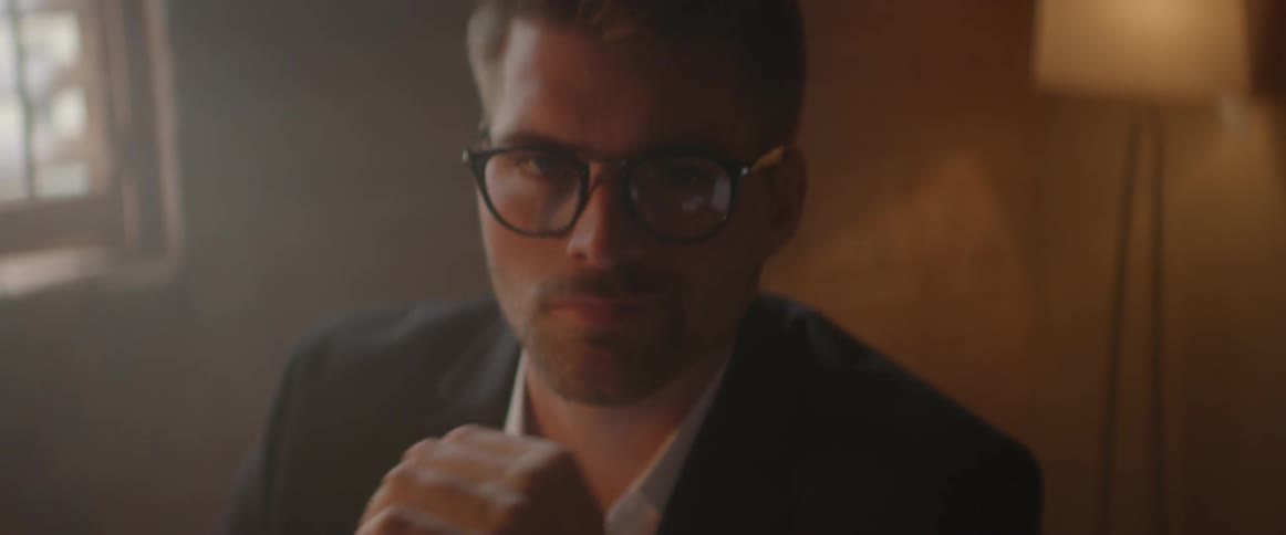 A man in business attire turns and looks toward the camera